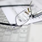 Glasses and pen on tax form and laptop.